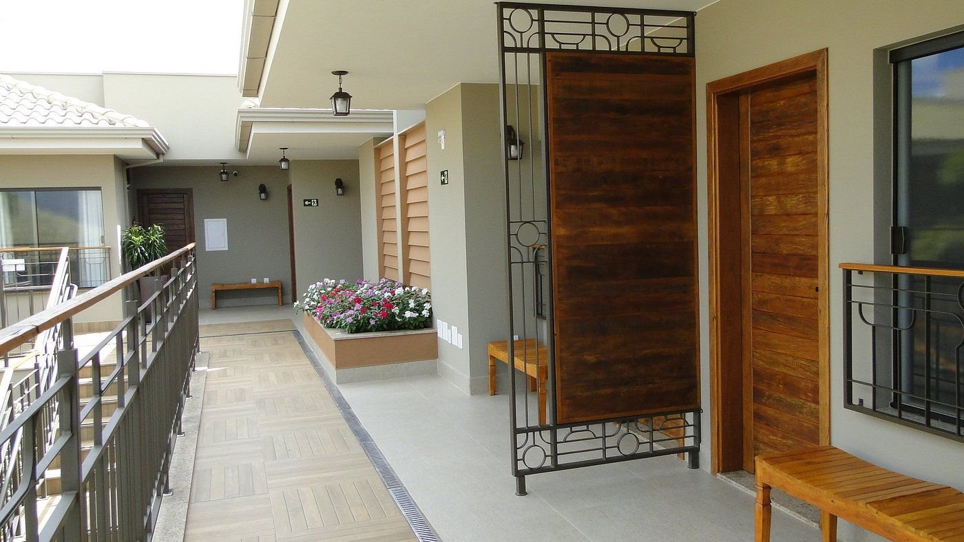 Passarela de acesso às suítes, com portas de madeira e floreira